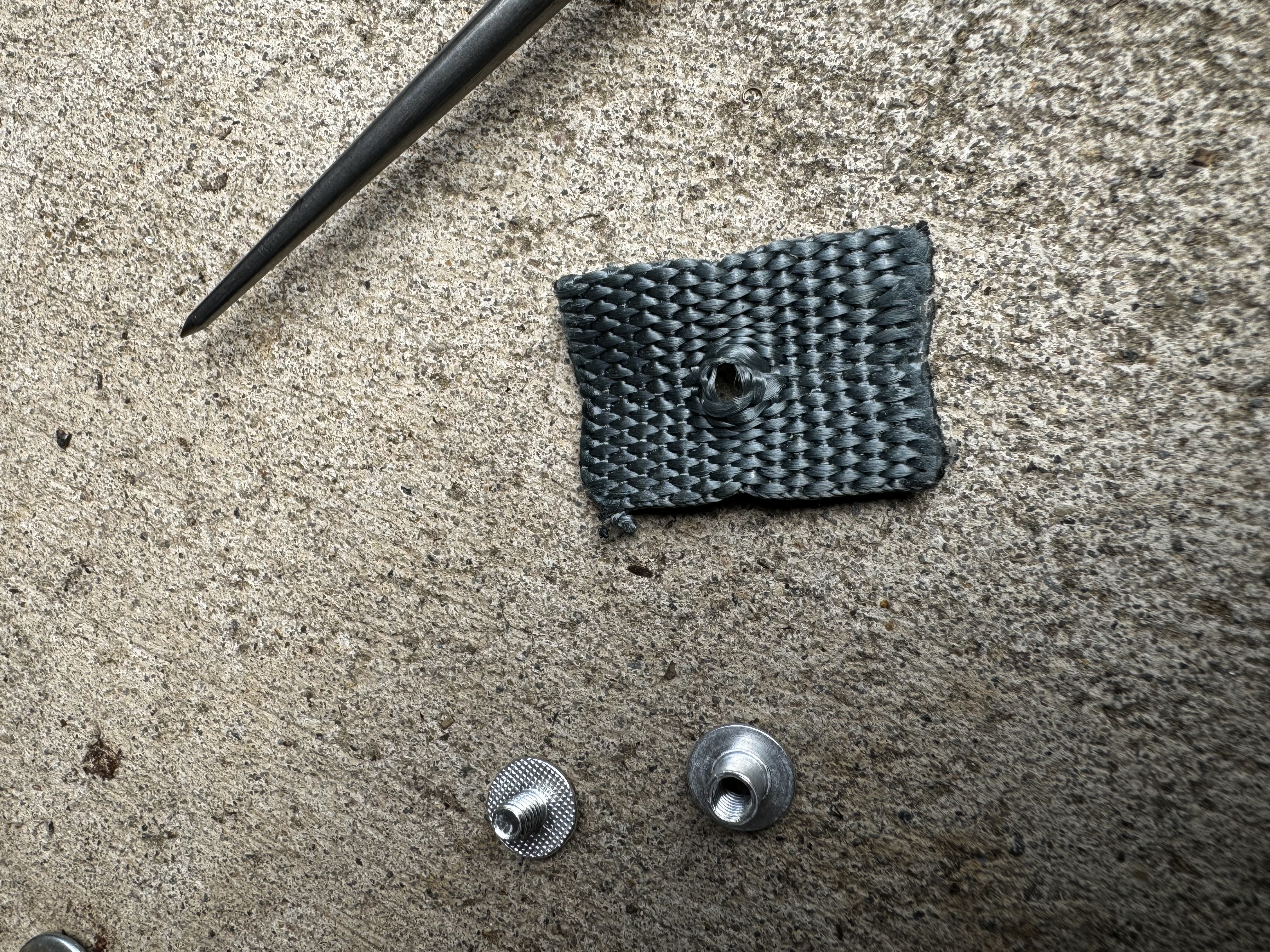 Picture of chicago screw and scrap piece of cordura with hole punched in it.